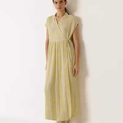 Vestido comprido amarelo claro com ténis brancos e parede branca