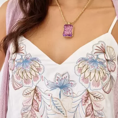 Colar com pendente roxo e corrente dourada usado com vestido branco bordado floral.