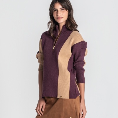 Mulher com camisola bordeaux e bege de malha com fecho e saia castanha
