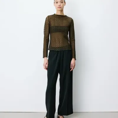 Mulher com camisa de renda marrom e calça preta larga