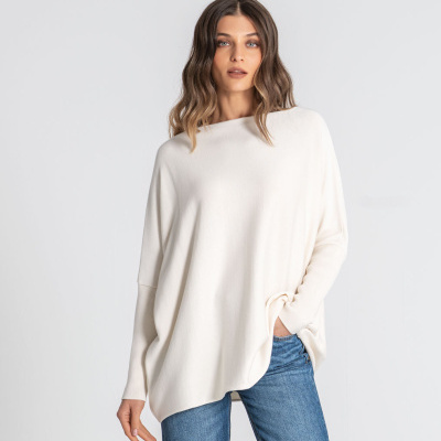 Mulher com blusão branco oversize e calças jeans azuis.
