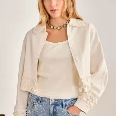 Mulher com camisa branca de botão, top branco e jeans azul claro com aplicações brilhantes