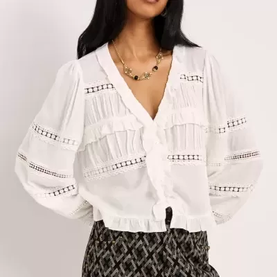 Blusa branca feminina com detalhes em renda e folhos além de calças pretas com padrão geométrico e botões na lateral