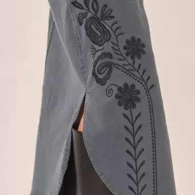 Vestido cinza com bordado floral preto e fenda lateral usado com bota preta de couro