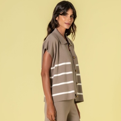 Mulher com colete cinza com riscas brancas e calças largas cinzentas