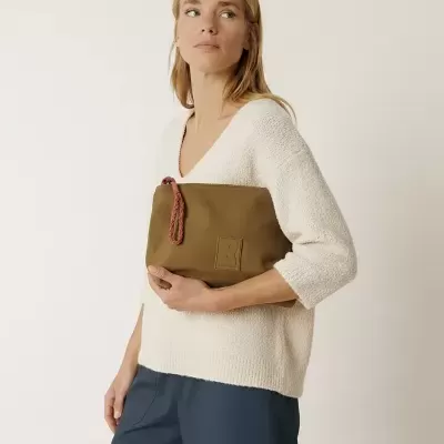 Mulher segurando carteira castanha com roupas creme e azul