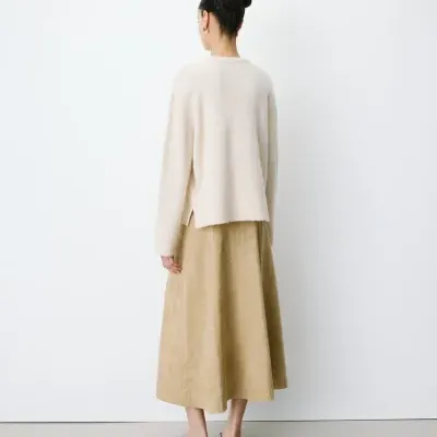 Mulher de costas com camisola bege clara e saia midi bege