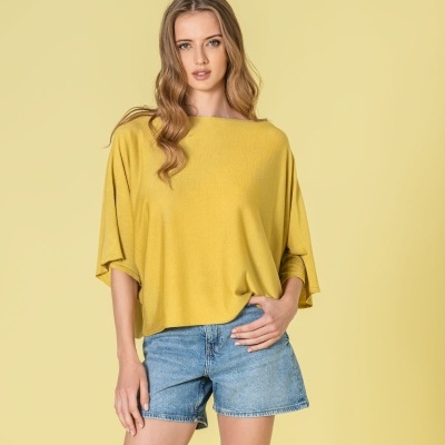 Mulher de camisola amarela e calções de ganga azuis em fundo amarelo