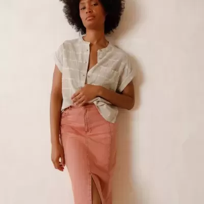 Mulher com camisa cinza clara e saia midi rosa com racha frontal