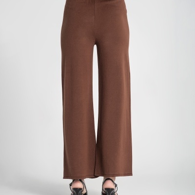 Calças castanhas largas vistas de costas com sandálias pretas