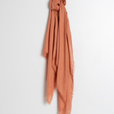 Lenço cor de terracota pendurado numa parede branca