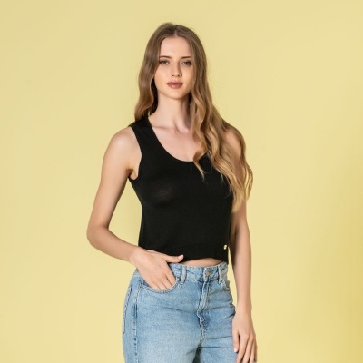 Mulher a vestir top preto de alças e jeans azul claro em fundo amarelo