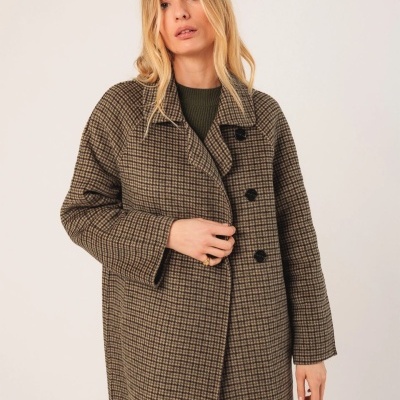 Mulher a usar casaco comprido xadrez castanho com botões pretos em fundo branco