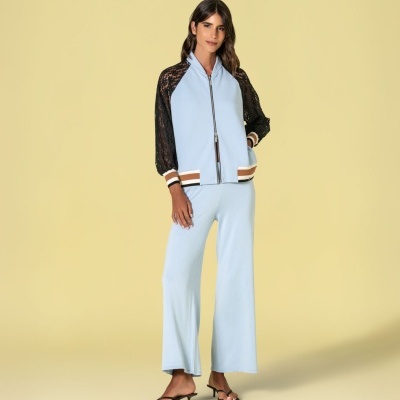 Conjunto feminino azul claro com casaco de mangas em renda preta, calças largas azuis e sandálias pretas de salto baixo