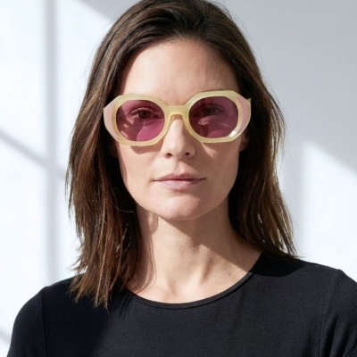 Óculos de sol amarelos com lentes rosa em modelo com camisa preta
