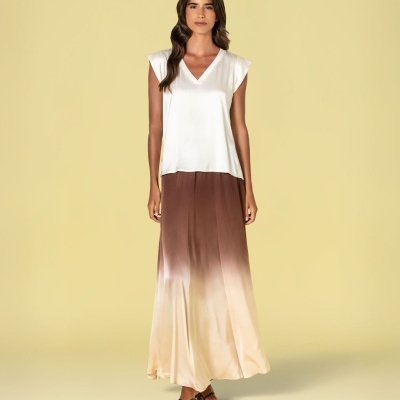 Mulher com blusa branca e saia comprida em degradé castanho a bege