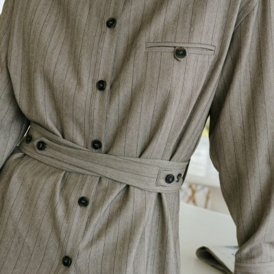 Vestido cinzento com riscas finas e botões pretos, cinto ajustado na cintura.