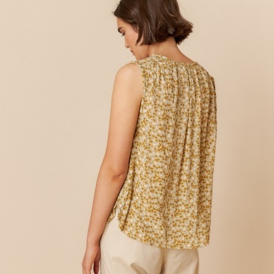 Blusa feminina sem mangas com padrão floral amarelo e branco vista de costas