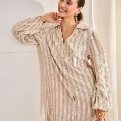 Vestido comprido feminino com riscas e renda, botões frontais e mangas compridas, mulher sorridente junto a uma parede interior