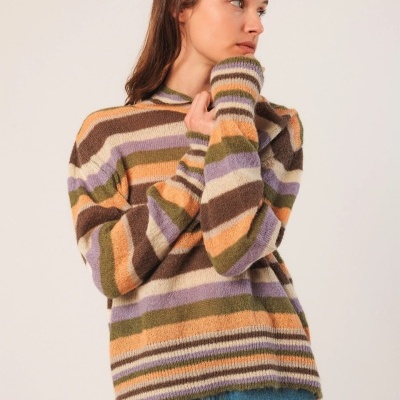 Camisola de malha riscada em vários tons usados por mulher com jeans azul.