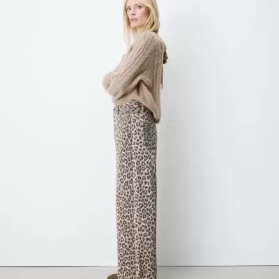 Mulher com camisola bege de malha e calças com padrão animal print