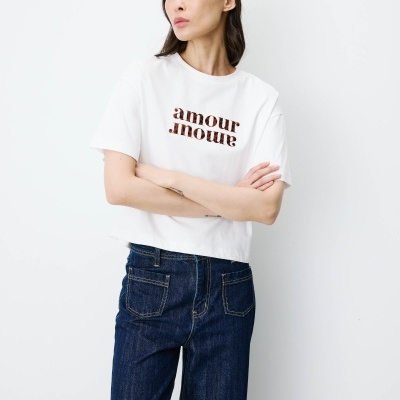 Mulher vestindo t-shirt branca com texto amour e calças de ganga azul escuro