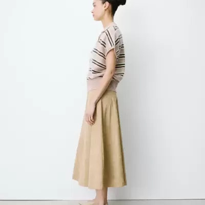 Mulher com camisola às riscas e saia midi bege em fundo branco