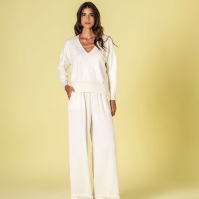 Mulher com camisola e calças brancas em fundo amarelo