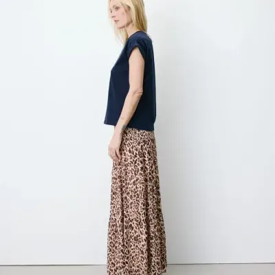 Mulher com t-shirt azul escuro e saia comprida animal print modelo lateral