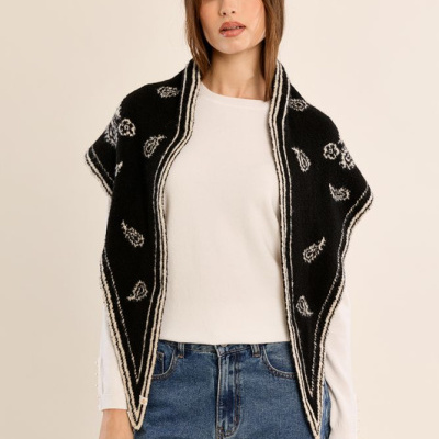 Mulher com colete preto com padrão branco, blusa branca e calças de ganga azuis