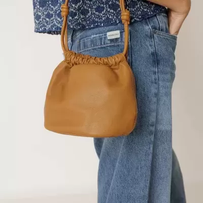 Bolsa em pele castanha com alça fina usada com roupa casual azul