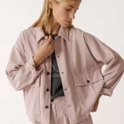 Conjunto rosa claro em tecido denim com botões e bolsos grandes, camisa preta por baixo