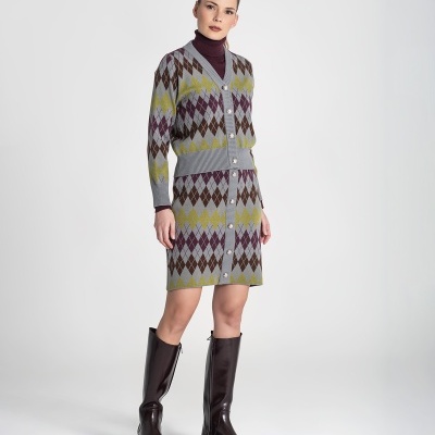 Mulher com casaco e saia de malha com padrão de losangos e botas pretas