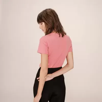 Mulher com t-shirt rosa e calças pretas vista de costas