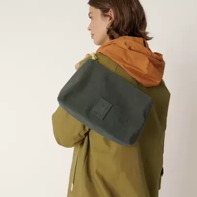 Mochila preta de tecido com mulher de casaco verde-oliva e capuz laranja