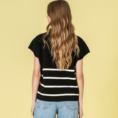 Camisola preta com riscas brancas e calças de ganga azuis claras vista de costas.