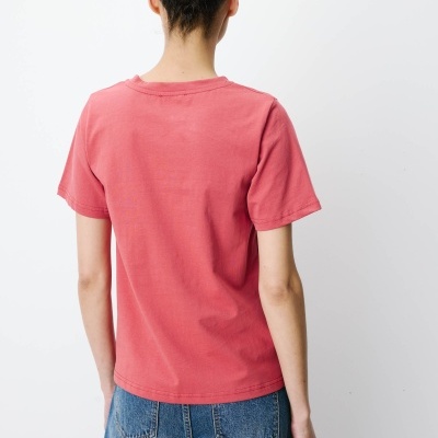 Pessoa de costas com t-shirt rosa e calças de ganga azuis.