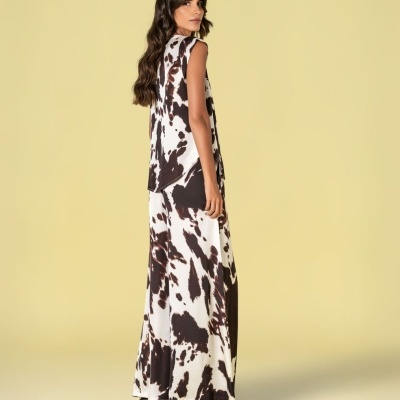 Mulher usando conjunto com estampa padrão animal em tons de preto, castanho e branco em fundo amarelo