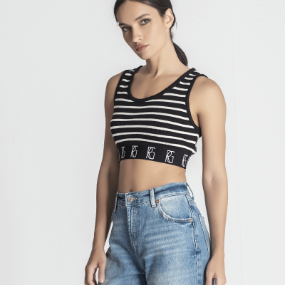 Top curto listrado preto e branco com letras na faixa elástica, usado com calça de ganga azul claro.