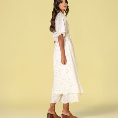 Mulher com vestido branco bordado e sandálias castanhas