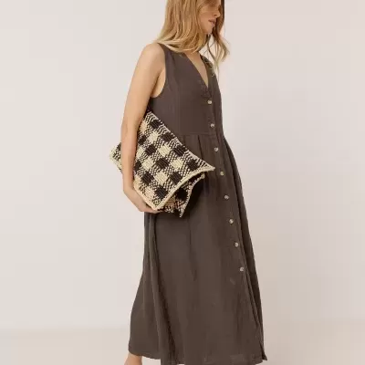 Mulher com vestido castanho escuro, carteira xadrez e mocassins.