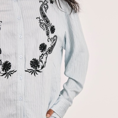 Camisa azul claro com bordados pretos e botões na frente