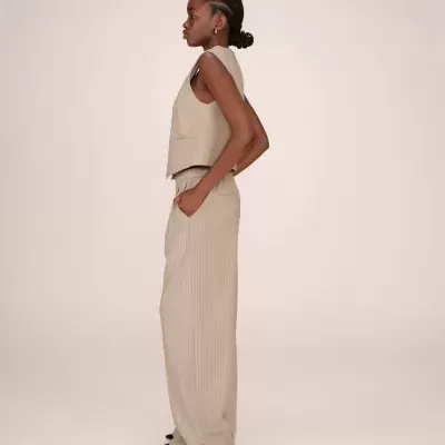 Conjunto bege riscado com colete e calças largas femininas em fundo neutro