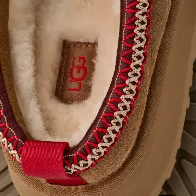 Sapatilha UGG em camurça castanha com interior felpudo branco e costura decorativa vermelha e bege