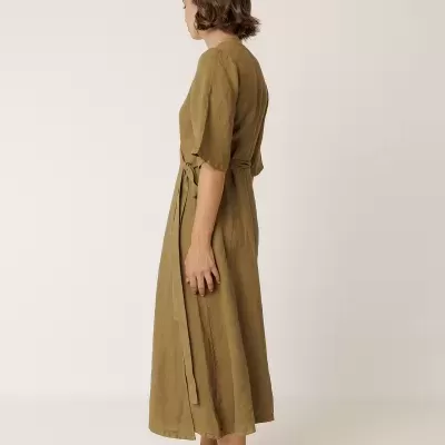 Mulher vista de lado com vestido midi verde-oliva e sandálias castanhas.
