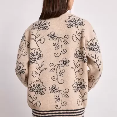 Casaco bege de malha com padrão floral preto, visto pelas costas.