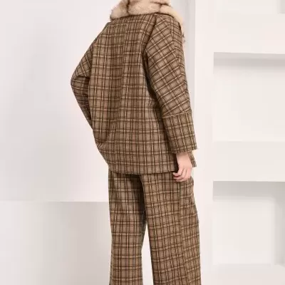 Conjunto xadrez castanho com colarinho de pelo falso, calças largas e ténis em ambiente interior