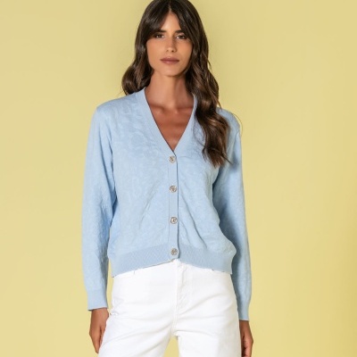 Cardigan azul claro com botões dourados e calças brancas
