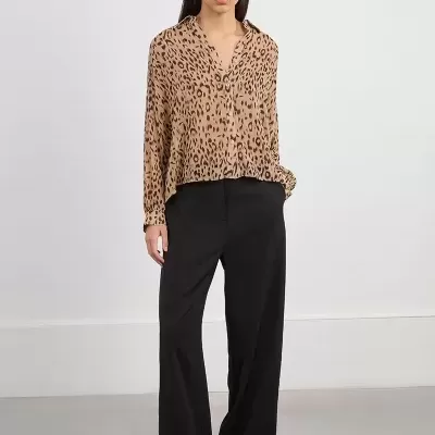 Mulher a usar camisa animal print bege com calças pretas largas e sapatos pretos