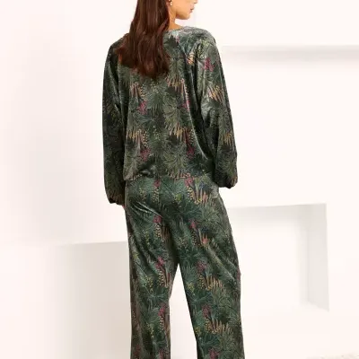 Conjunto de roupa com padrão de folhagem em tons verdes, amarelos e vermelhos visto de costas numa sala clara com carpete.